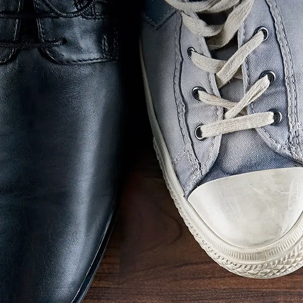 Zwei Schuhe, einer schwarz und schick und ein ausgetretener Sneaker, symbolisieren das Thema Unternehmensnachfolge