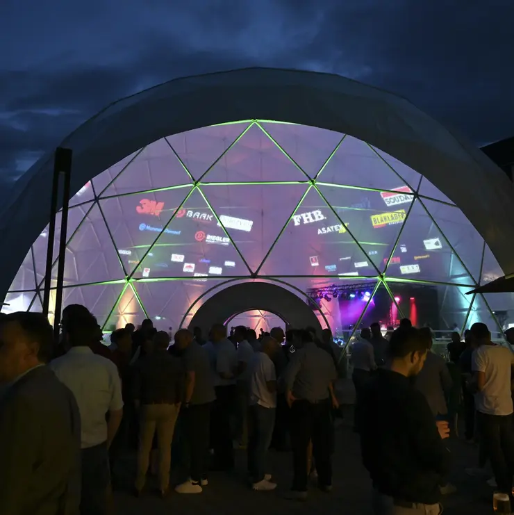 Événement Nordwest Kuppeltreffen avec de nombreux participants qui se tiennent à l’extérieur, de nuit, devant une tente igloo éclairée