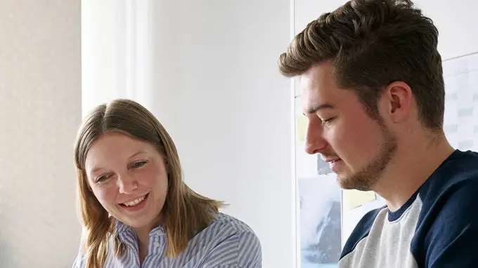 Zwei junge Kollegen, ein Mann und eine Frau sprechen über ein Projekt. 