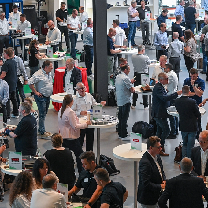 De nombreuses personnes se tiennent autour de tables mange-debout pour des discussions professionnelles