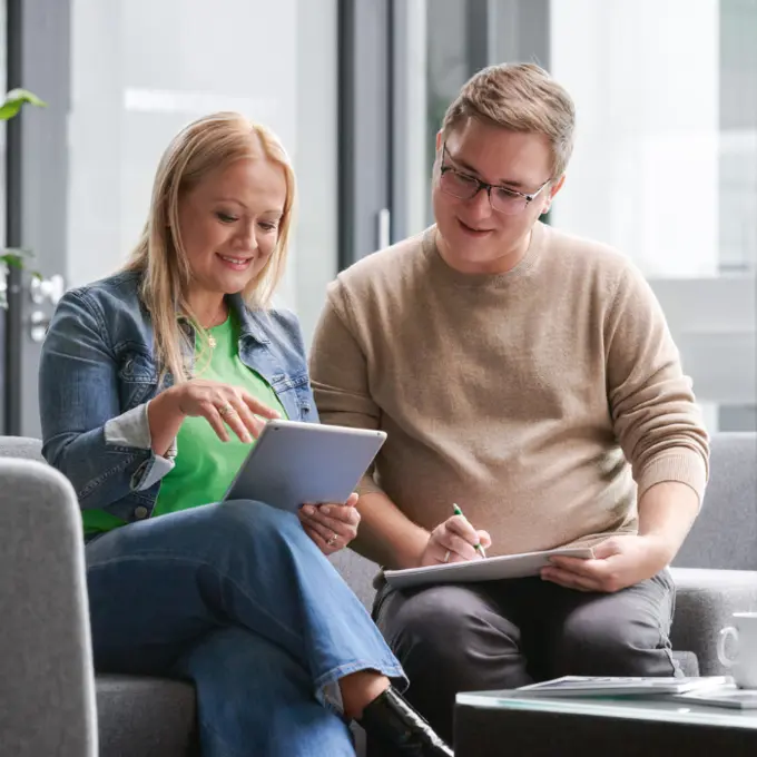 Twee collega’s zitten samen en bespreken iets.